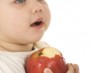 Little girl eating red apple