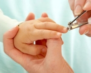 Human hands clipping baby's fingernails with clipper