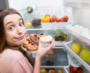 Woman with sweet food near refrigerator