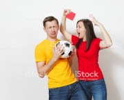 European angry aggressive young woman, football referee in red uniform show red soccer card, propose man player with soccer ball retire from field isolated on white background. Sport football concept